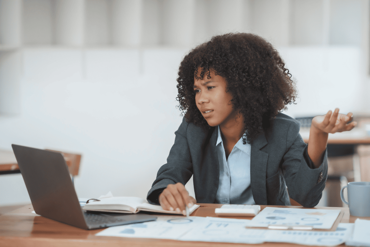 Une femme devant son ordinateur, exprimant des questions ou frustrations lors de la gestion d’un contrôle fiscal CIR.